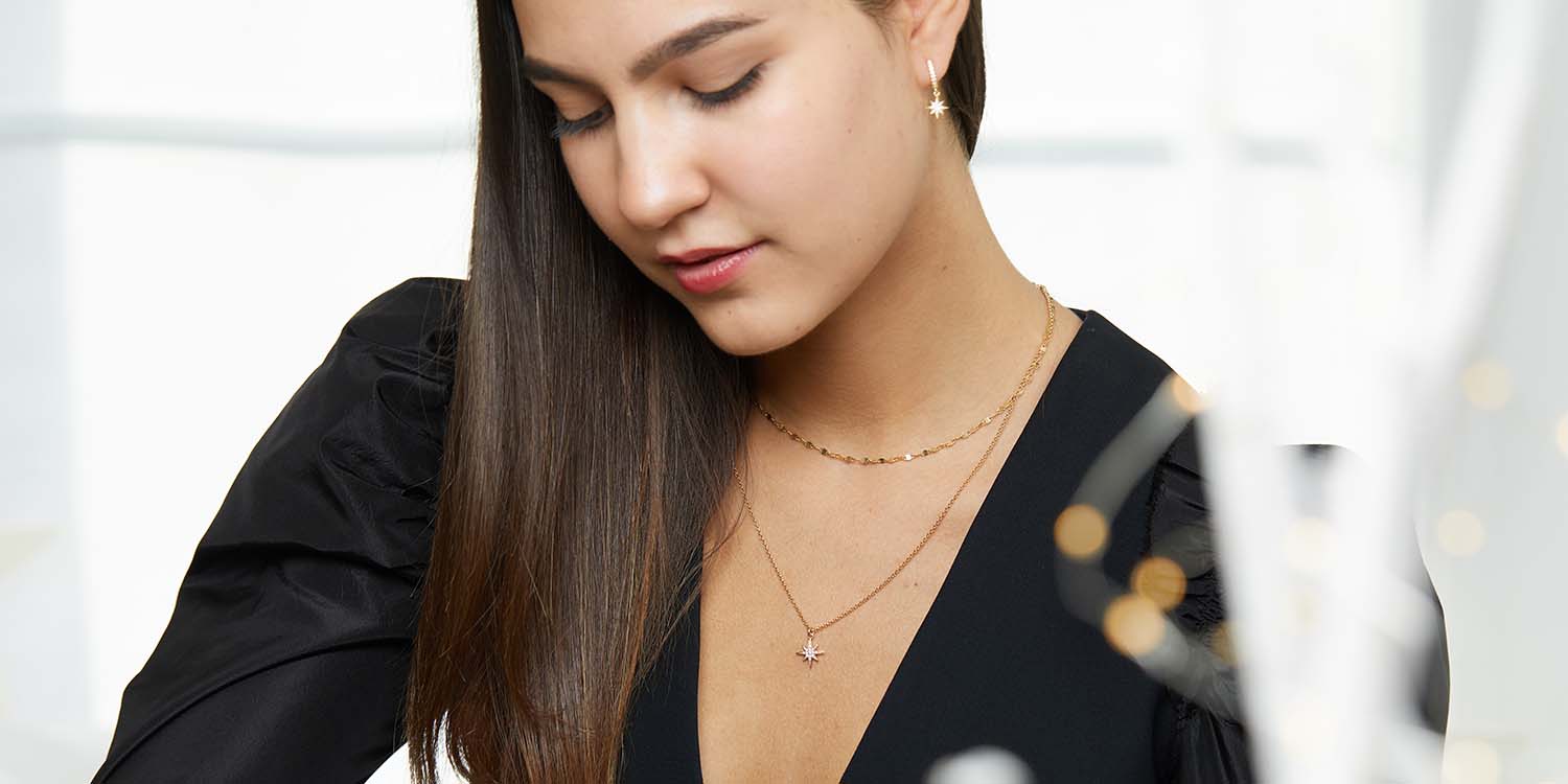 Frau trägt elegante goldene Halsketten und Ohrringe in minimalistischem Design